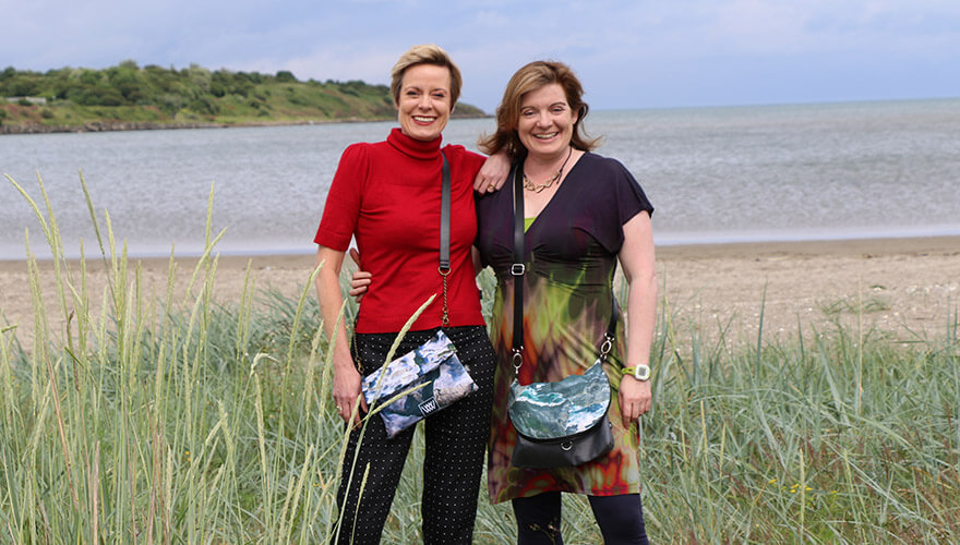 Jacki Parker and Nicole McKenna stand among reeds on beach