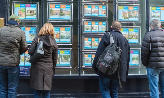 people looking at houses in estate agent window