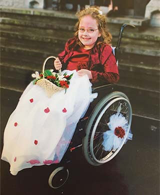 a young izzy keane sits in a wheelchair decorated with flowers