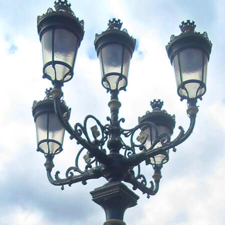 the black cast-iron lanterns of the five lamps against a cloudy sky