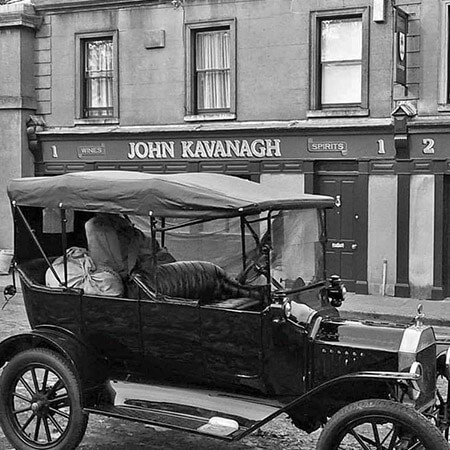 black 19th century parked in front of john kavanagh's pub sign
