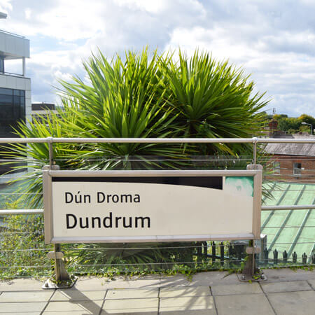 dundrum luas stop sign set in front of green trees and blue skies