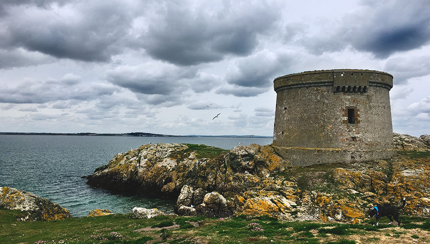a stone martello tower sits along the rocky coastline