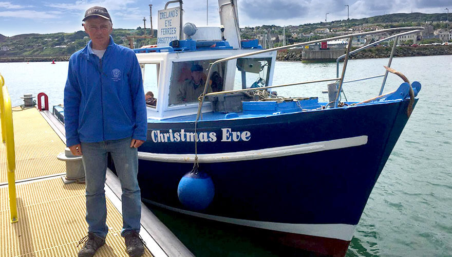 ken doyle stands on the pier beside his blue and white boat