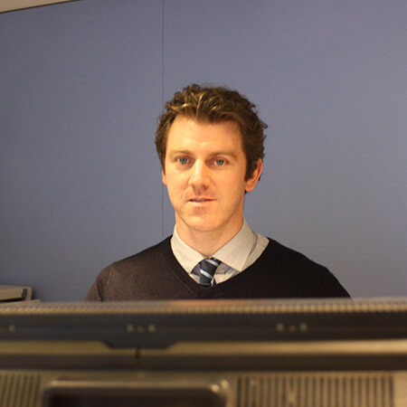 portrait photo of Andrew Harris standing at screens in the traffic control room