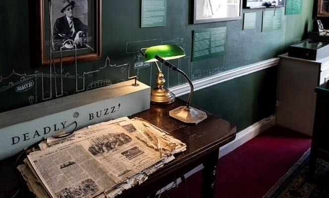 old newspapers, wooden desk and green antique lamp in the irish times room at the little museum