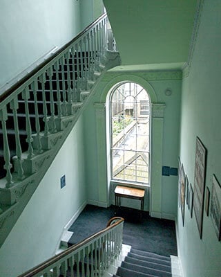 a georgian window shines light on the stairs of the james joyce centre