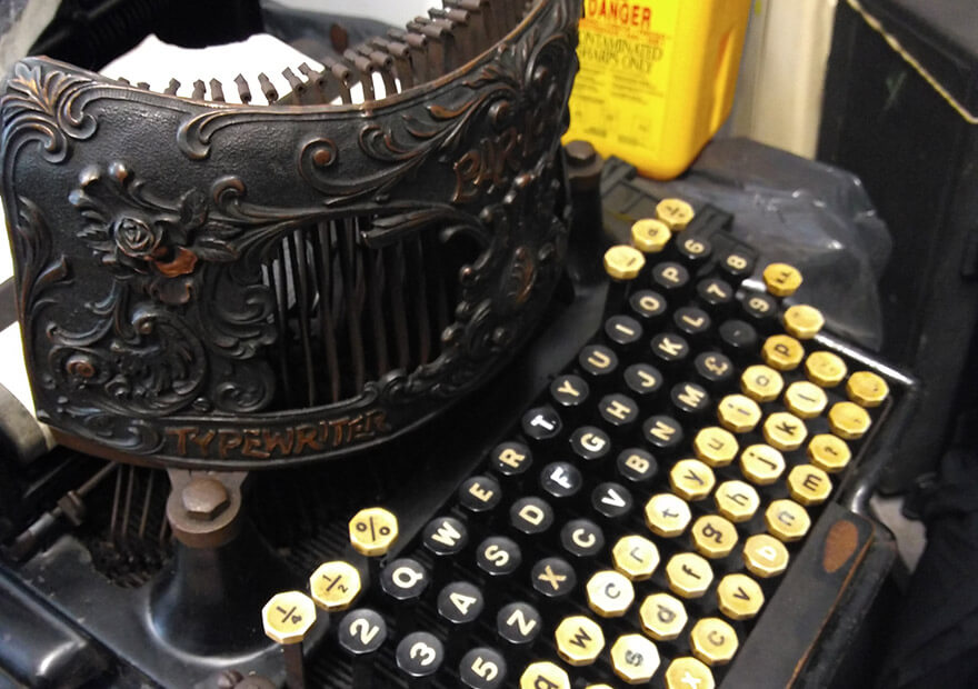 a black Bar-Lock typewriter with two separate keyboards and an elaborately designed curving copper plate