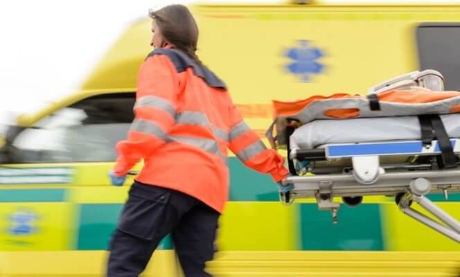 A paramedic pulls a stretcher from an ambulance