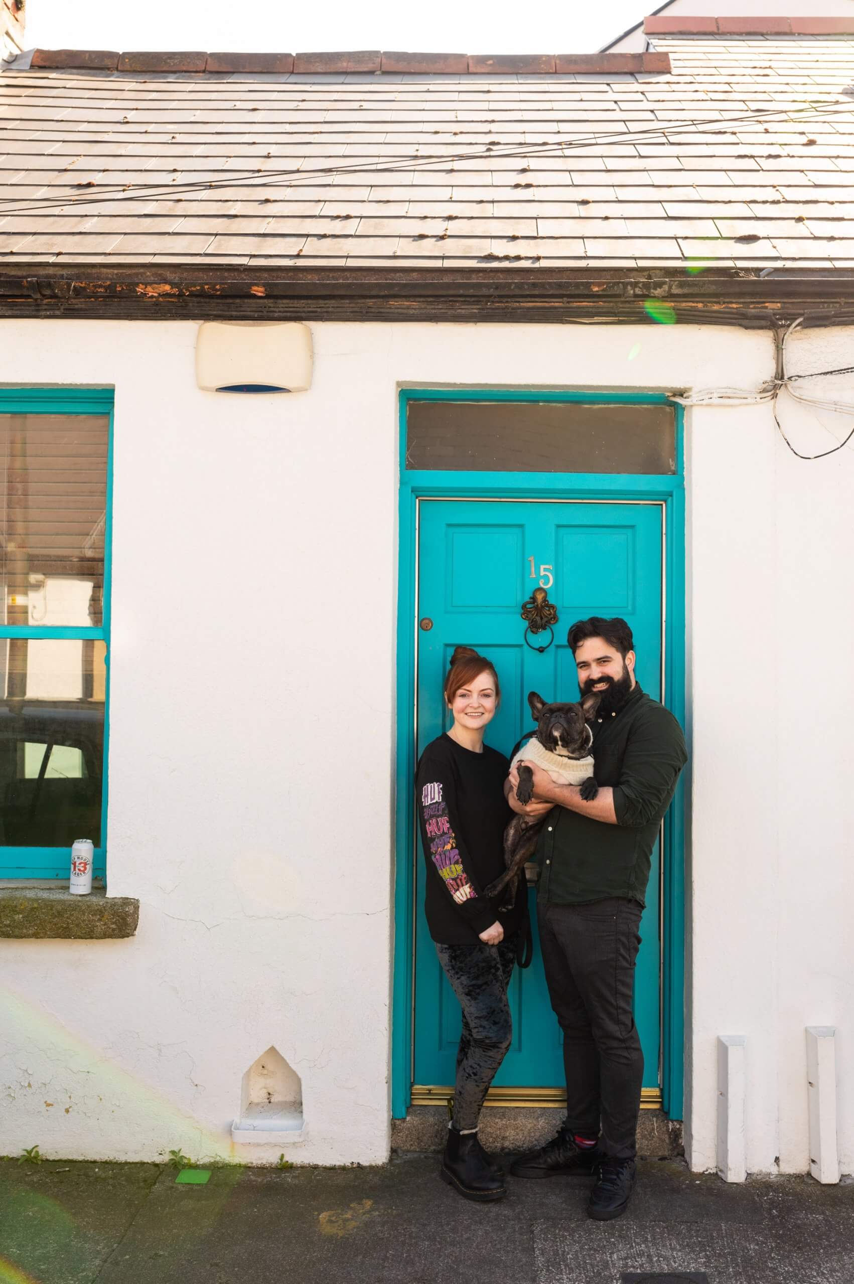 A couple and their dog pose at their front door